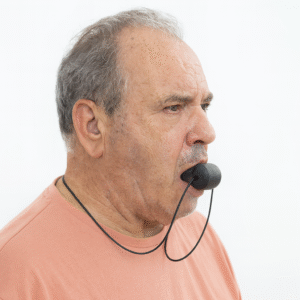Homem idoso a fazer exercício mandibular com aparelho de treino facial preto