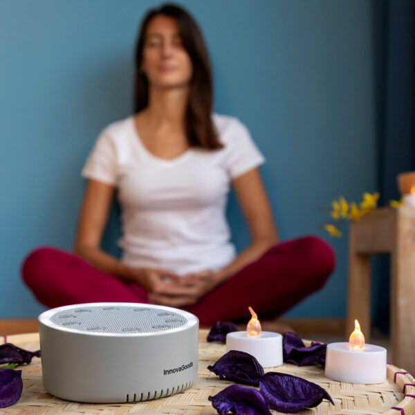 Máquina de Ruído Branco para Relaxamento e Meditação Mulher sentada a meditar com máquina de ruído branco ligada ao lado em ambiente calmo