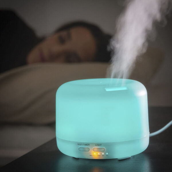 Difusor Ultrassónico Azul com Luz LED – Aromaterapia e Humidificação Difusor de aromas ultrassónico azul ligado na mesa de cabeceira