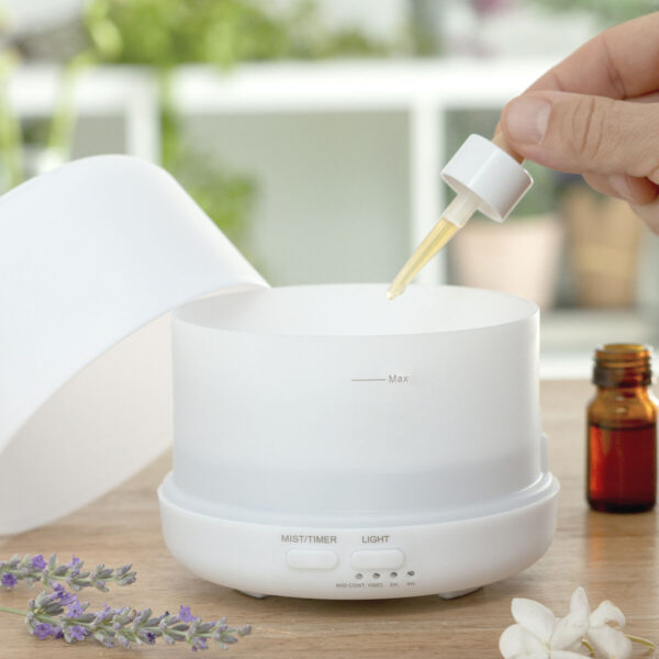 Difusor Ultrassónico Branco LED em uso – Aromaterapia e Purificação do Ar Pessoa a utilizar difusor de aromas ultrassónico branco com luz LED