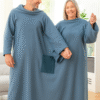 Casal entre 50 e 60 anos sorrindo no sofá com cobertor duplo azul InnovaGoods, ideal para conforto, inverno e relaxamento.