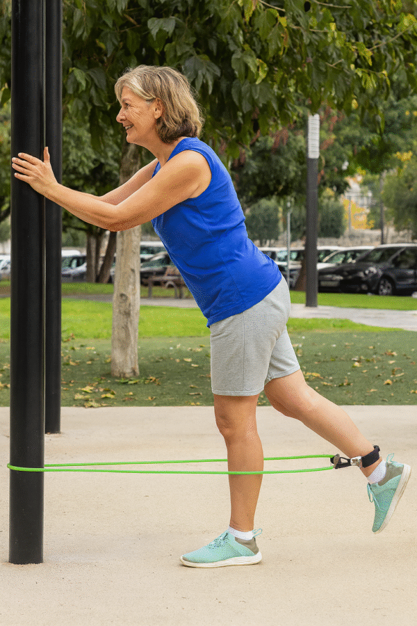 V0103182cExercício com elástico de resistência para idosos – treino ao ar livre Mulher de 50-60 anos a treinar com elástico de resistência no parque