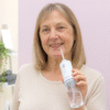 V0103481aIrrigador Oral Portátil Denter InnovaGoods – 220 ml, 3 modos, bateria 2000 mAh Mulher de meia-idade utilizando irrigador oral portátil recarregável InnovaGoods, mostrando sorriso saudável e higiene oral eficiente.