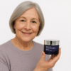 S05144883Creme Facial Institut Esthederm Intensive Hyaluronic – Mulher madura Mulher madura com expressão simpática segurando o creme facial Institut Esthederm Intensive Hyaluronic, símbolo de hidratação profunda e rejuvenescimento natural.